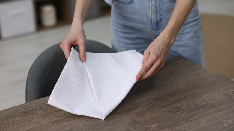 hands folding cloth napkin