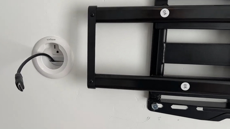 a black cable emerging from a wall grommet