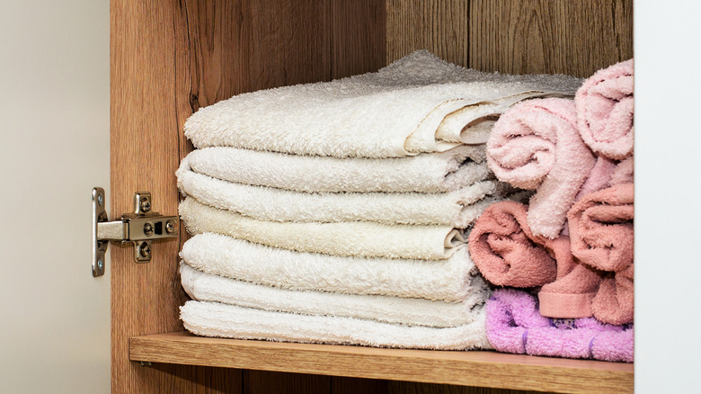 A narrow vertical bathroom linen cabinet with door on a concealed hinge.