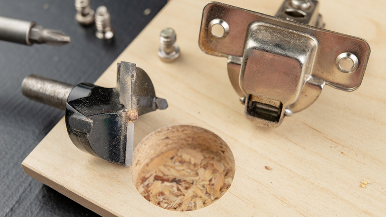 A hole drilled for a concealed European cabinet hinge on a wood panel