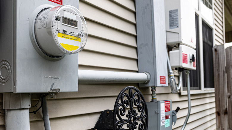 A meter base and meter, solar inverter, and disconnect mounted to the exterior wall of a house