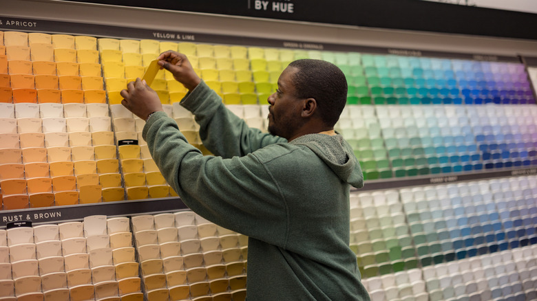 Man picking out a color swatch card at a store that sells paint