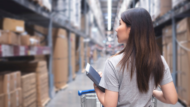 A woman pushes a cart through a hardware store