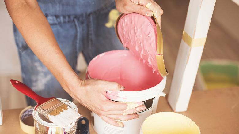 A woman opening an old can of pink paint