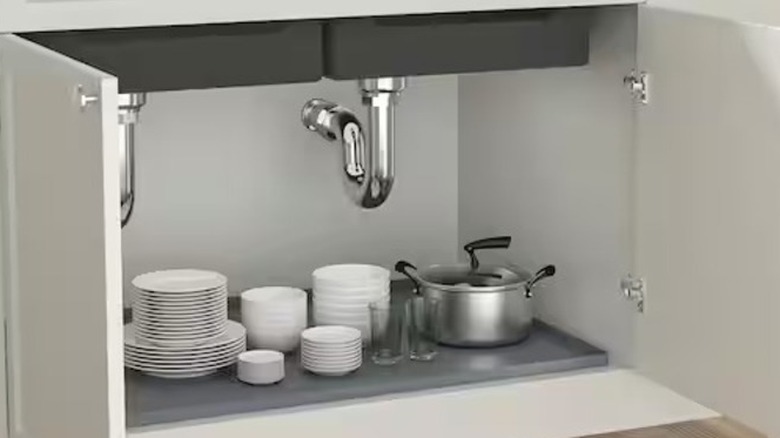 A gray mat with raised edges sits underneath two sinks, with a row of bottles on its surface