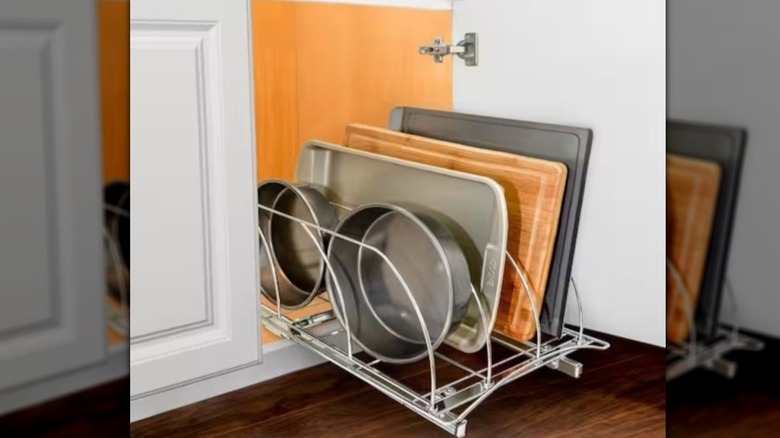 A metal silver tray holding cake pans, cutting board, and cookie sheet
