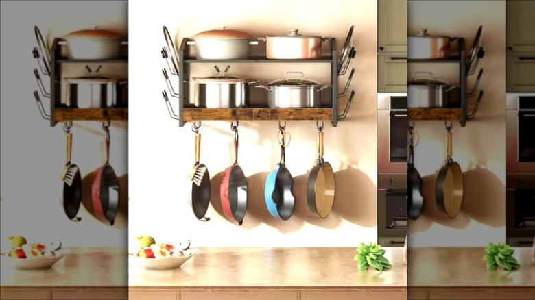 A two-tiered cookware organizer with hanging pots and pots sitting on two shelves