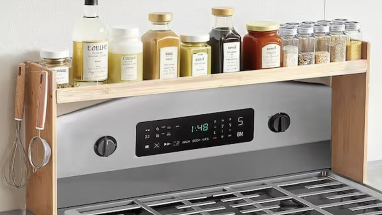 A wood shelf sitting above a stovetop, with bottles and jars organized on the shelf