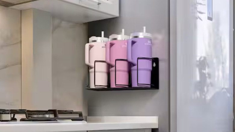 Three Stanley cups sit against one side of a fridge for storage