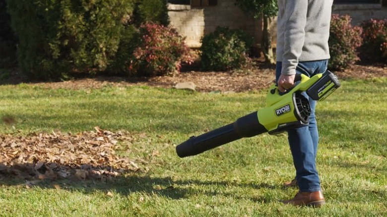 Person blowing leaves in the lawn with a Ryobi 40V HP Brushless Whisper Series blower