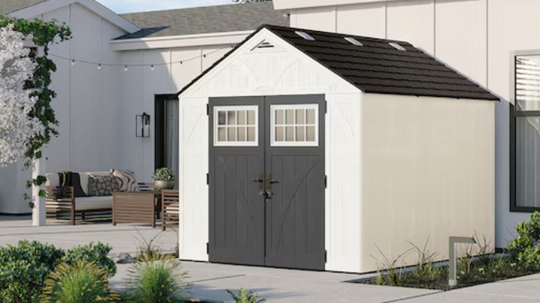 A white Tremont storage shed with a black doorway and roof