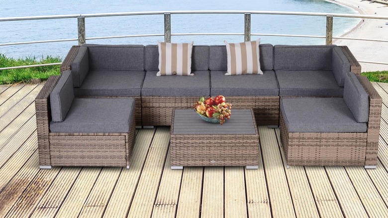 Gray outdoor rattan furniture on a deck overlooking a beach