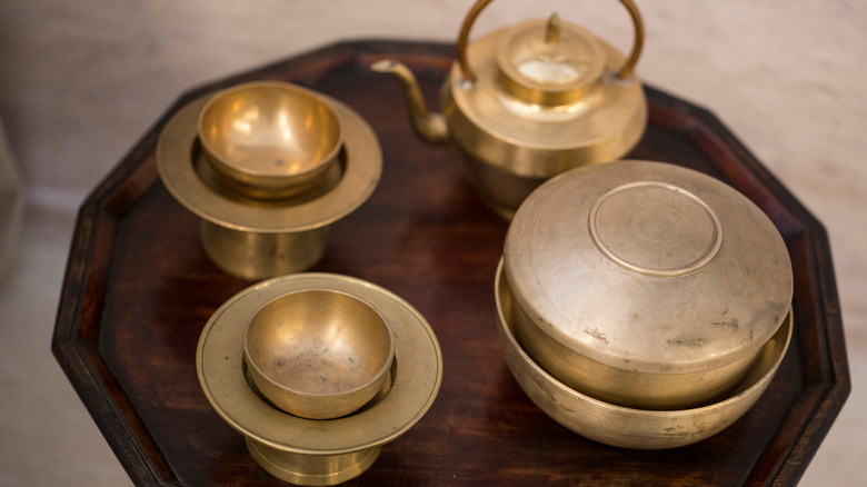 Image of four peices of traditional Korean Bangjja bronzeware on a wooden tray.