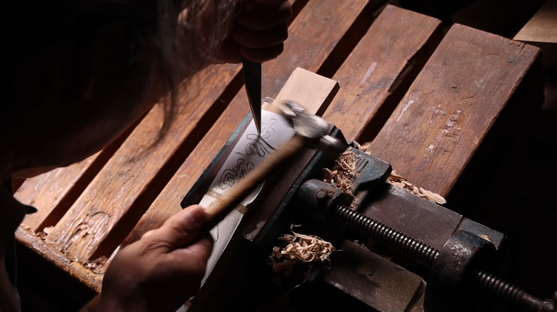 Mokjogakjang master carving shapes into a board.