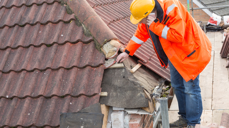 A worker inspects roof damage