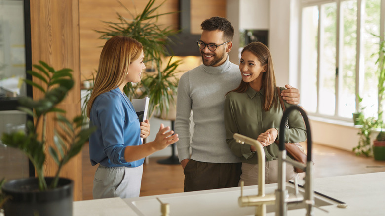 A shop assistant helps a couple in a kitchen showroom