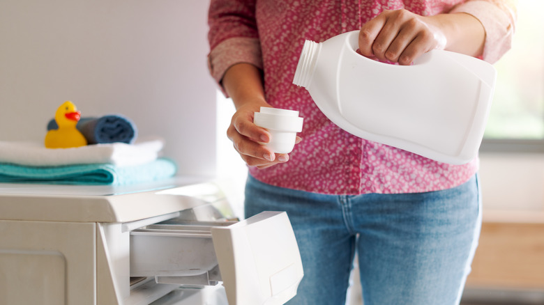 person pouring laundry detergent