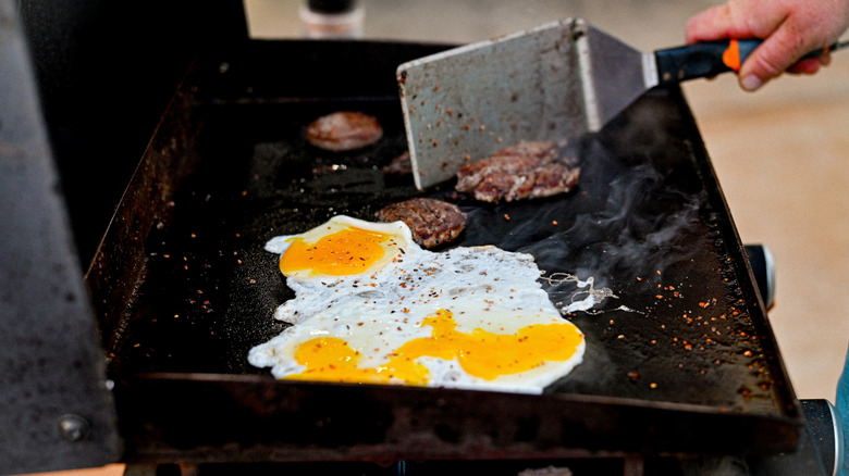 Eggs and burgers being cooked on a Blackstone griddle top
