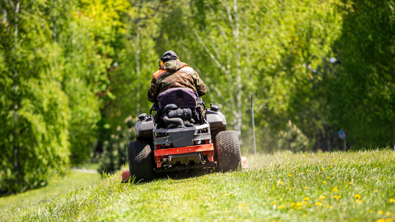 a person riding a lawn mower across a green lawn