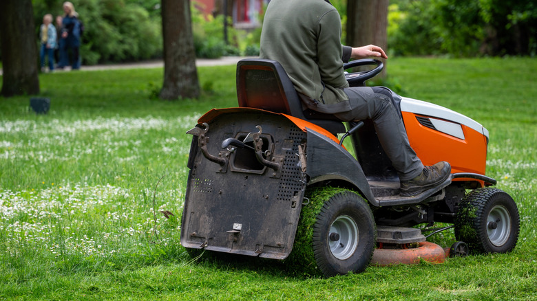 Man using a riding lawn mower to cut grass