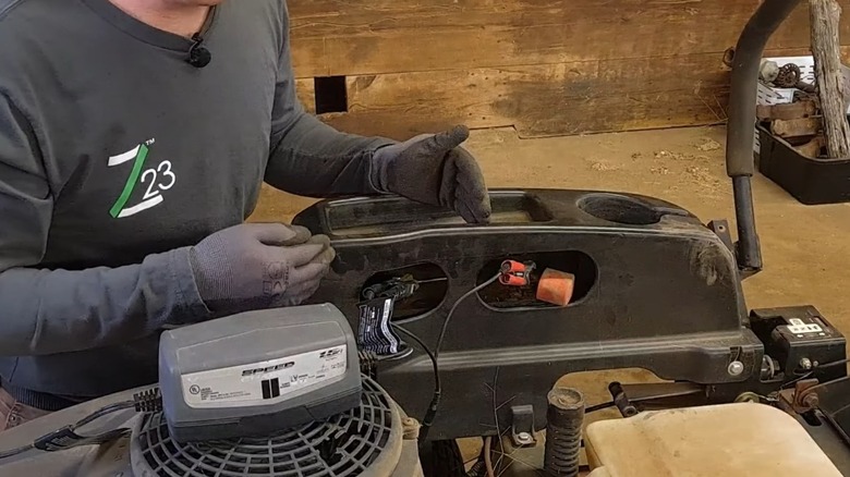 Man setting up the positive and negative cables to charge his riding lawn mower