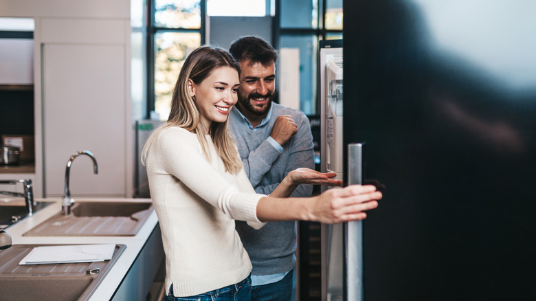 A couple opening a refrigerator at home.