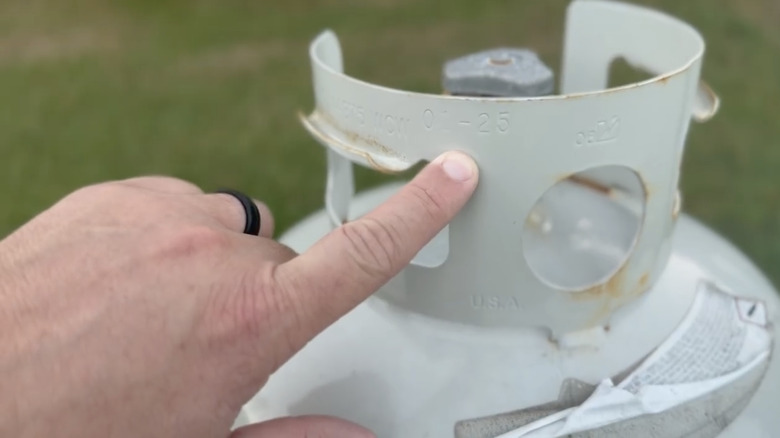 finger pointing at propane tank date