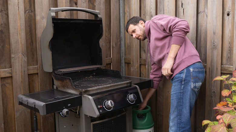man adjusting propane tank on gas grill
