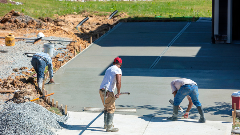 Skilled laborers smooth a residential concrete driveway