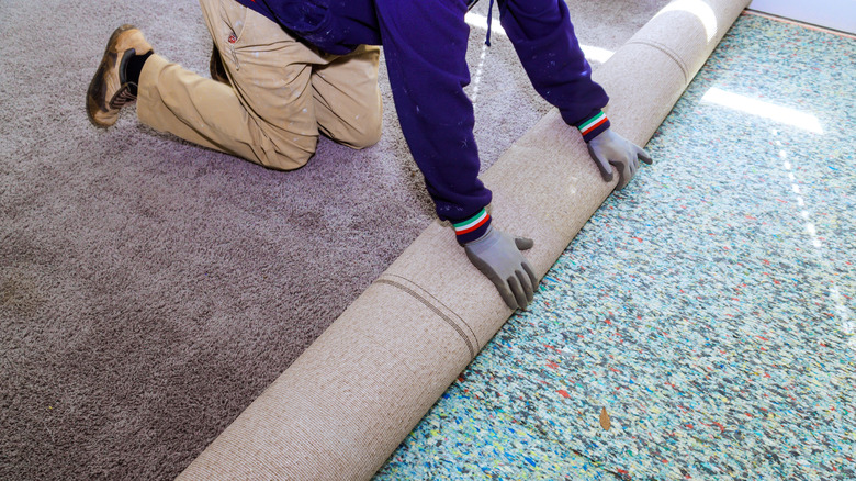 An installer rolls a new carpet pad out on a floor