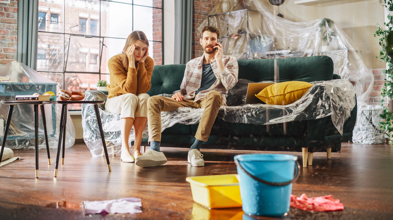 A stressed out couple sits in a flooded living room