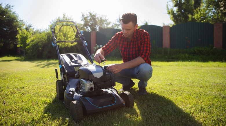 Man holding his lawn mower's oil cap and looking at the dipstick