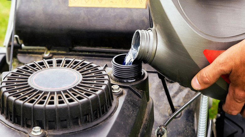 Person adding gas to a lawn mower