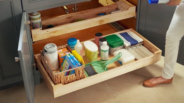 A full-width pull-out tray at the base of an under sink cabinet for easy access to storage