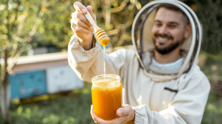 Beekeeper holding a glass jar filled with honey