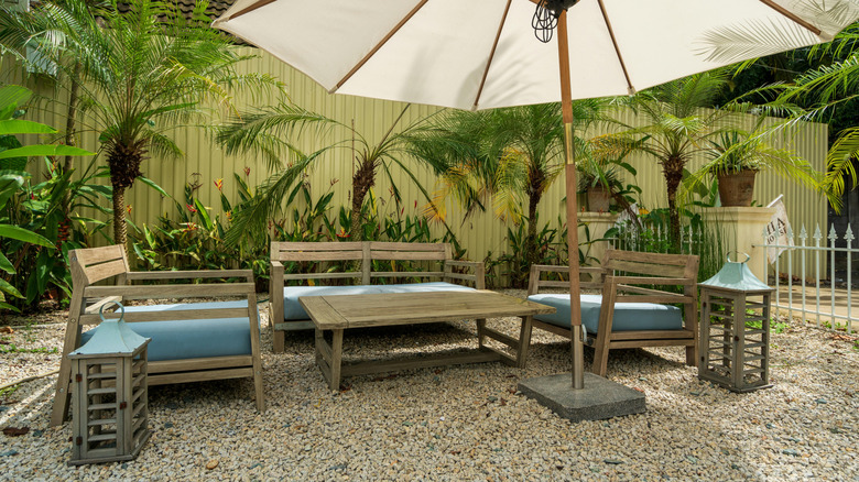 Furniture and umbrella on a gravel patio. Concrete isn't necessary for building an outdoor gathering space.