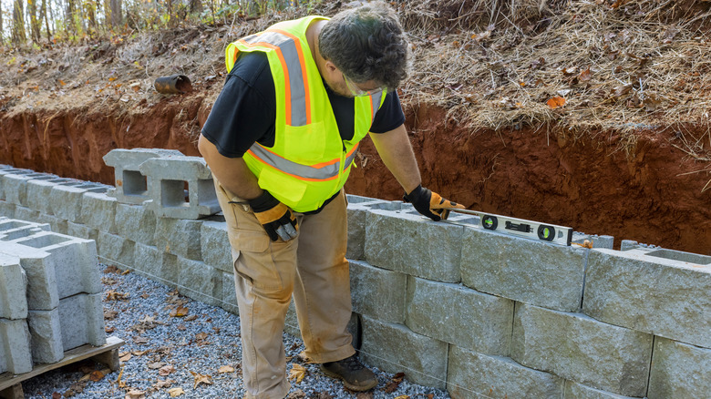 A professional is levelling concrete blocks on a retaining wall
