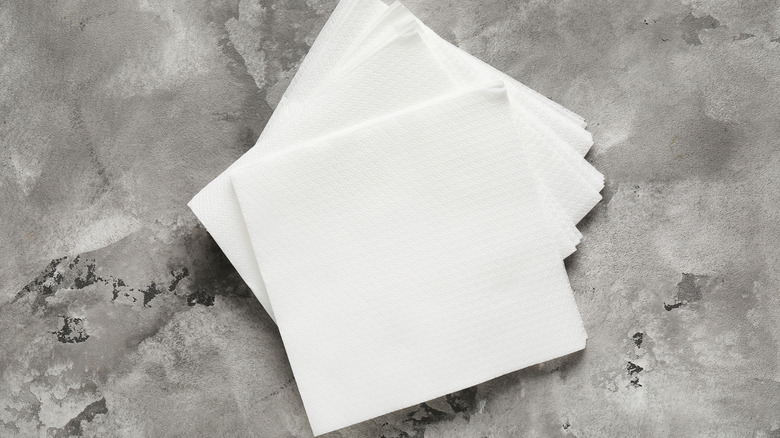 a stack of paper napkins sit on a gray floor