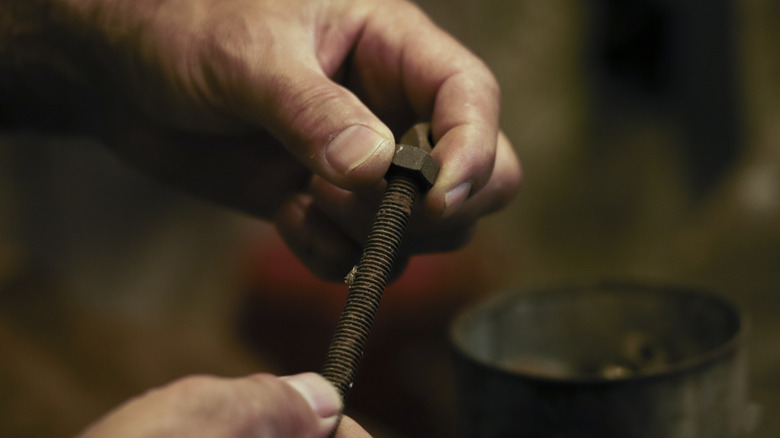 A man holds a long bolt