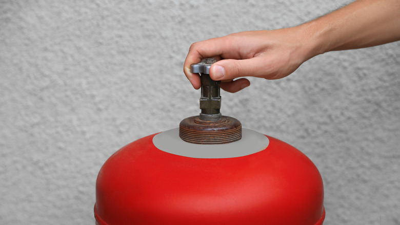 A close up of a hand on a propane tank