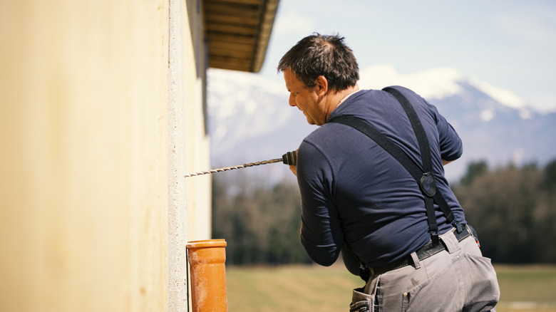 A man drilling into a concrete wall