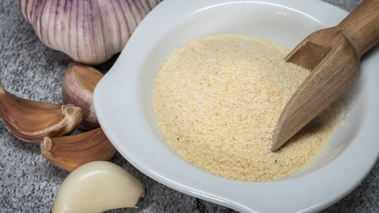 Bowl of garlic powder surrounded by cloves of garlic