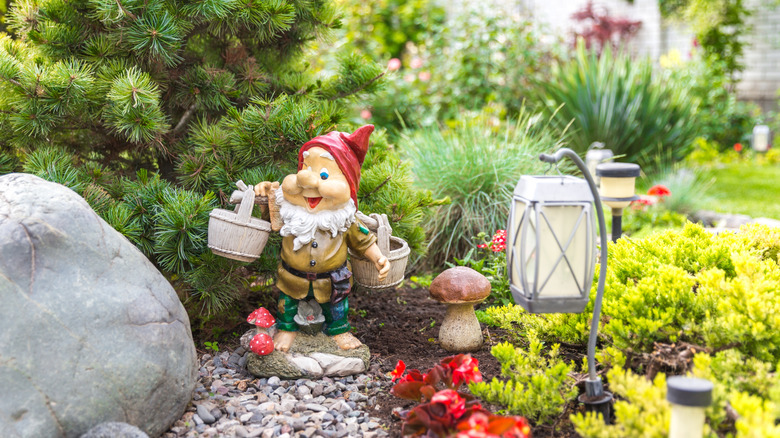 Garden gnome and decorative mushroom underneath a small tree