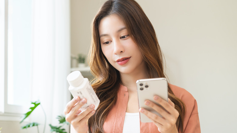 A woman reading the label on a prescription bottle