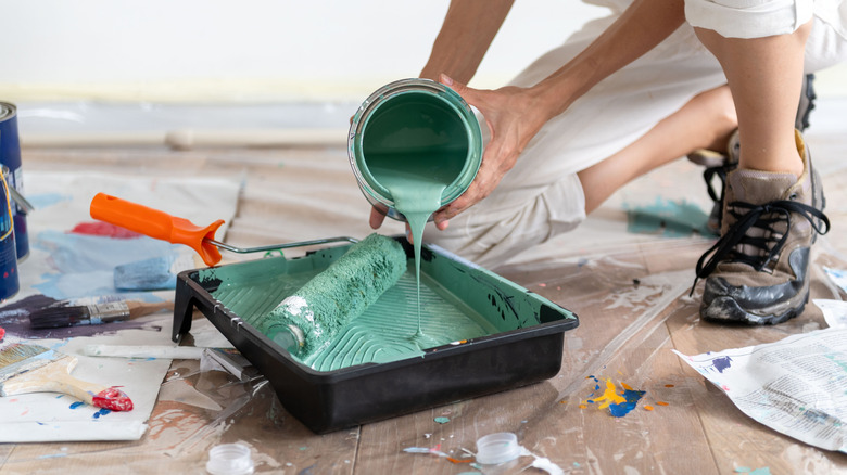 A person is pouring paint into a paint tray.