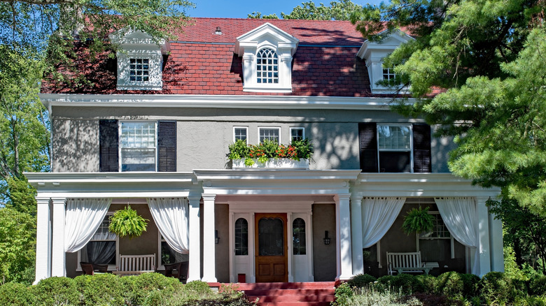 A stately house with curtains draping the front porch