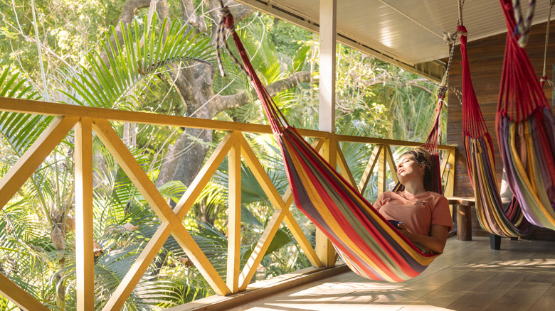 A woman relaxing in a hammock in a covered porch