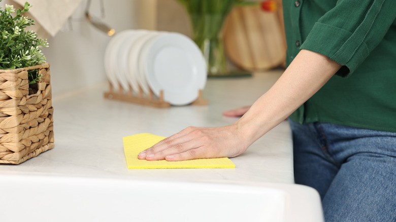 Person wiping down kitchen counter with a sponge