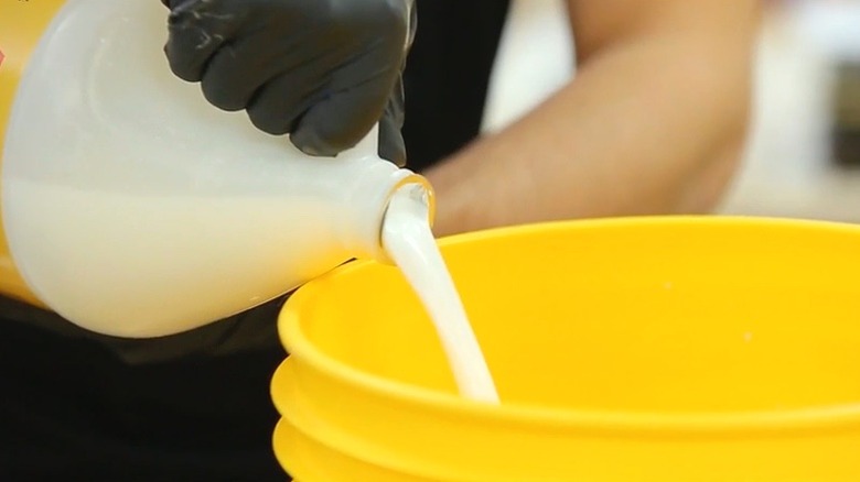 Person pouring acrylic latex fortifier into concrete mix