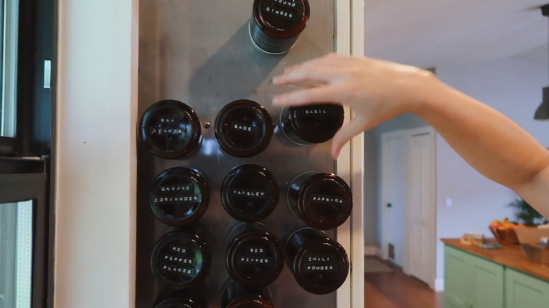 Vertical magnet spice storage jars on side of kitchen cabinet